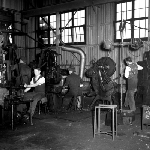 Cover image for Photograph - Several workers on the Titan factory floor engaged in various processes of toolmaking