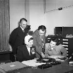 Cover image for Photograph - "Kindergarten of the Air", Miss Anne Dreyer choosing some music for demonstration at the Hobart studios of the Australian Broadcasting Corporation (ABC)