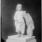 Cover image for Photograph - studio portrait of young girl barefoot on pedestal leaning on rock fossil [glass plate]