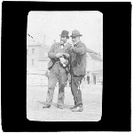 Cover image for Photograph - glass lantern slide - Joseph Graves pointing finger and  receiving box of matches from Mr Ford.  "Two old ship owners".