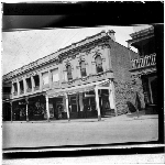 Cover image for Photograph - glass lantern slide - street scene showing menswear shop (N. Adelson?) and Greek restaurant - unidentified location, possibly Hindley St, Adelaide
