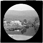 Cover image for Photograph - glass lantern slide - Unidentified view of large rural double-story, gabled-roof weatherboard residence and out buildings on rivers edge - Huon River area?