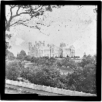 Cover image for Photograph - glass lantern slide - Hobart - Domain - Government House - exterior view showing front picket fence and gardens- sepia toned slide