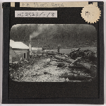 Cover image for Photograph - North East Tasmania after flooding (shows fallen timber debris beside a timber house  - c 1929) / Fred Smithies [lantern slide]