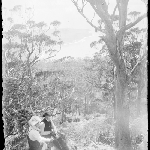 Cover image for Photograph - Glass negative - Parish picnic [man and woman in bush setting, man sitting on boulder, woman standing]