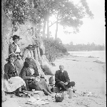 Cover image for Photograph - Glass negative - Parish picnic [group having picnic on sandy beach.  Jetty in background - area?]