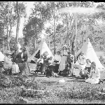 Cover image for Photograph - Glass negative - Parish picnic (see also NS4077/1/54) [group seated in front of tents in bush setting]
