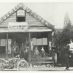 Cover image for Photograph - Exterior view of Croswell's Butchery, shows meat hanging outside on veranda, delivery boy on horse with basket, motor bike outside shop, men and children on veranda
