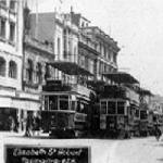 Cover image for Photograph - Hobart - Elizabeth Street showing Bursary building and adjoining buildings and no. 11 and 49 trams. Taken by "H.J.H."