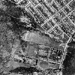 Cover image for Photograph - Aerial view of Sandy Bay showing Rifle Range site with University Physics Department huts, Queenborough Cemetery & Nelson Road