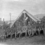 Cover image for Photograph - Soldiers in front of tent, with other buildings on each side - sepia print