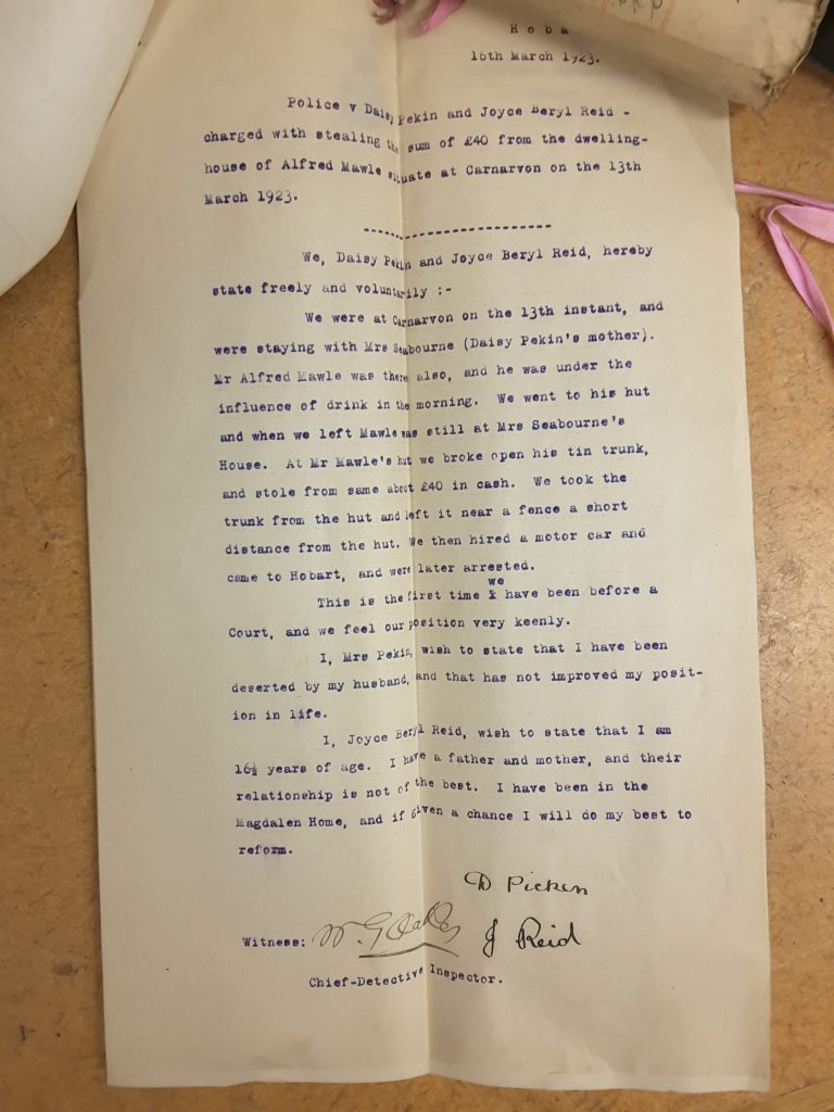 A photo of an old piece of paper. Text reads: “16th March 1923. Police v Daisy Pekin and Joyce Beryl Reid – charged with stealing the sum of 40 pounds from the dwelling – house of Alfred Mawle situate at Carnarvon on the 13th March 1923. We, daisy Pekin and Joyce Beryl Reid, herby state freely and voluntarily :- We were at Carnarvon on the 13th instant, and were staying with Mrs Seabourne (Daisy Pekin’s mother). Mr Alfred Mawle was there also, and he was under the influence of drink in he morning. We went to his hut and when we left Mawle was still at Mrs Seabourne’s house. At Mr Mawle’s hut, we broke open his tin trunk, and stole from the same about 40 pounds in cash. We took the trunk from the hut. we then hired a motor car and came to Hobart, and were later arrested. This is the first time we have been before a court, and we feel our position very keenly. I, Mrs Pekin, wish to state that I have been deserted by my husband, and that has not improved my position in life. I, Joyce Beryl Reid, wish to state that I am 16 and a half years of age. I have a father and a mother, and their relationship is not of the best. I have been in the Magdalen Home, and if given a chance I will do my best to reform.”