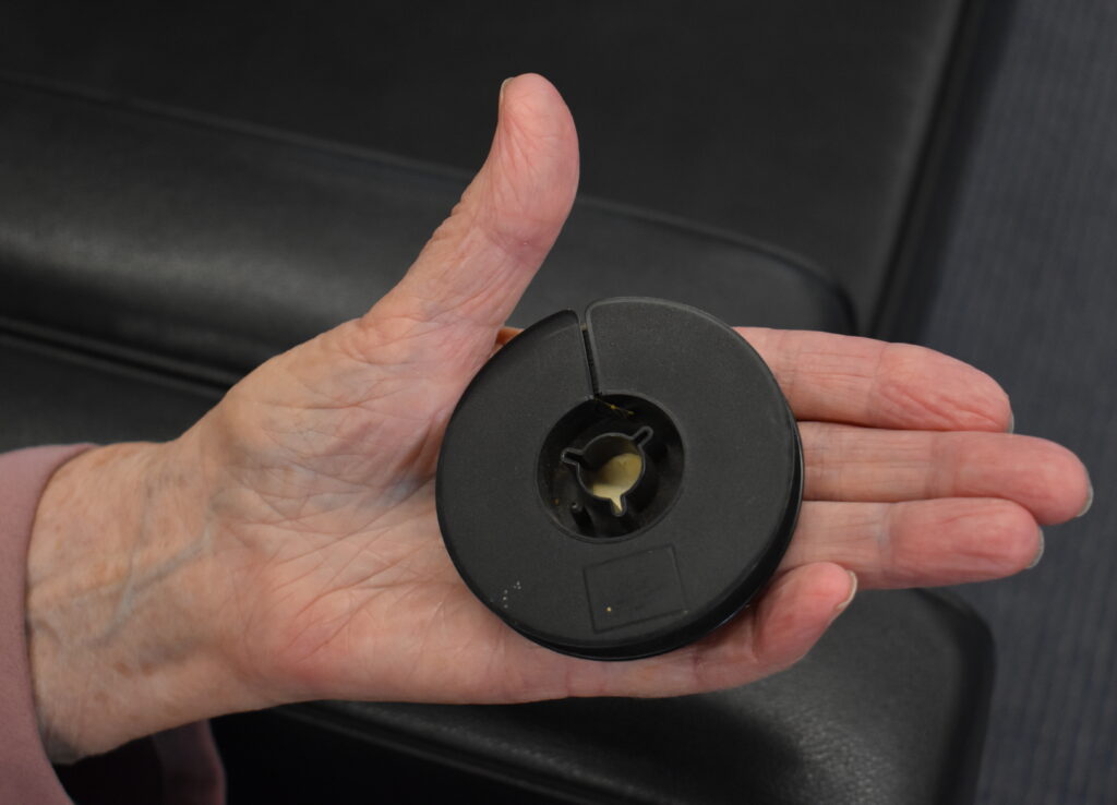 Close up image of a hand holding a black plastic circular reel of 8mm film