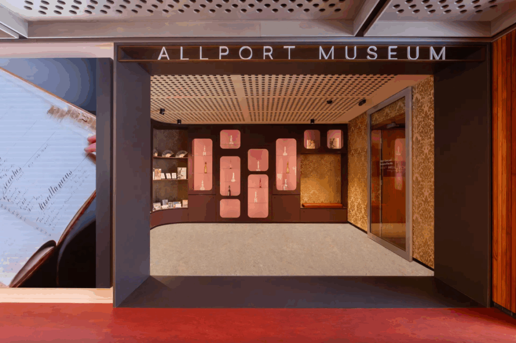The Hobart Library ground floor. The Wide entryway to the Allport Museum. Orange lino transitions to grey. The ceiling is grey metal with grated holes.
