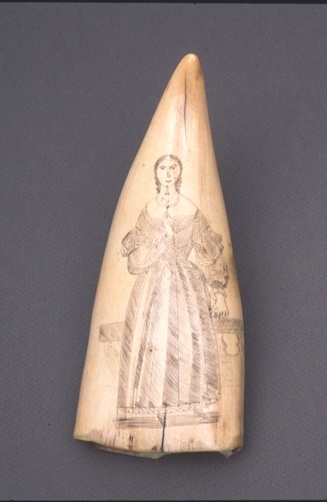 A whale tooth with a picture of a woman in a dress on it.