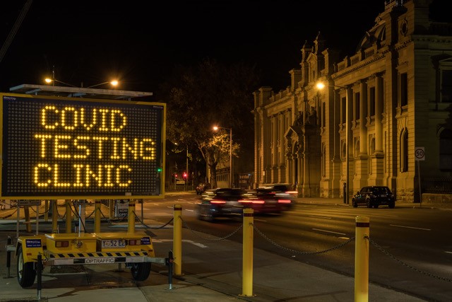 A digital work sign next to a road. Text reads: "covid testing clinic".