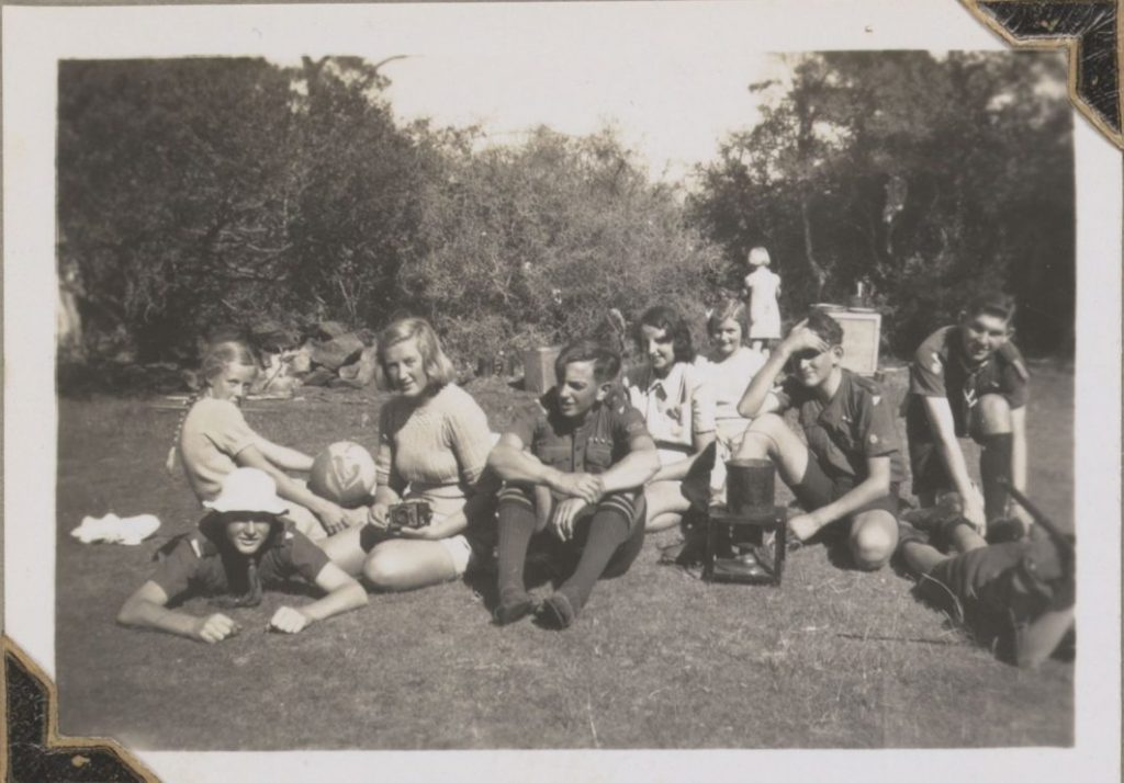 an old black and white photo of 8 people sitting on the grass