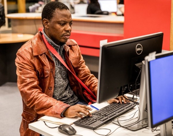 A man sitting at a desk working on a computer.