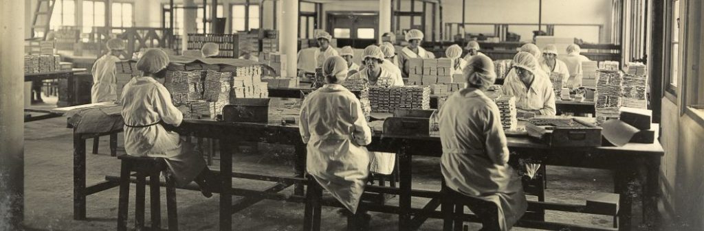 An old black and white photo of workers inside the Cadbury factory making chocolate