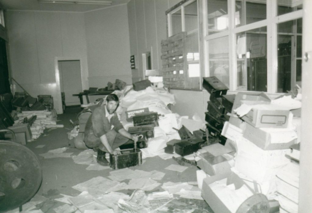 A man standing in a room sorting through old files.
