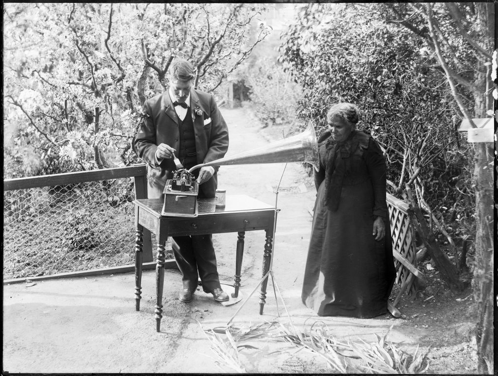 A photo of a man with and an Aboriginal woman Using an old sound recording instrument.