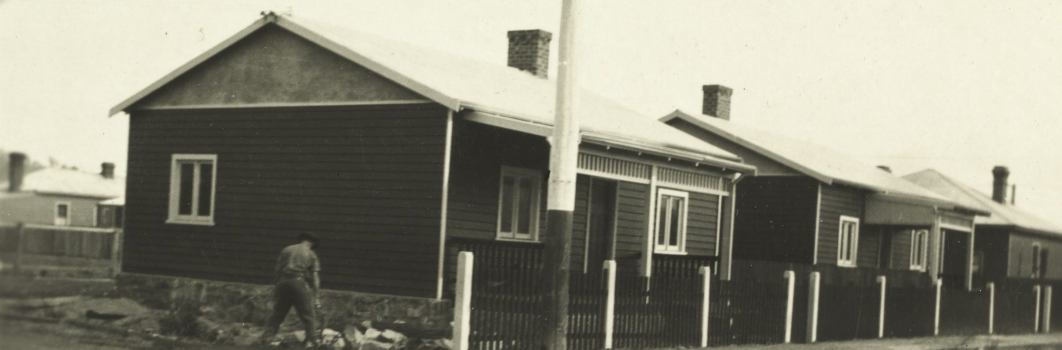 A black and white photo of a line of 3 houses as seen from the street
