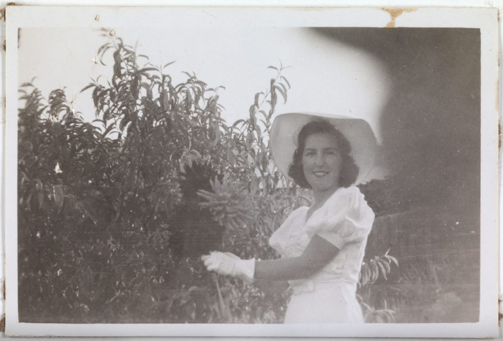 An old blakc and white photo of a woman holding flowers.