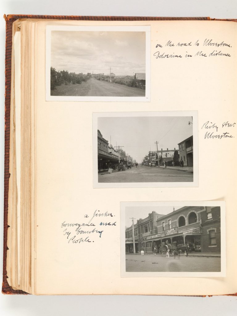 A page from an old photo album. there are 3 photos. 1 from a countryside road. and 2 are pictures of city streets.