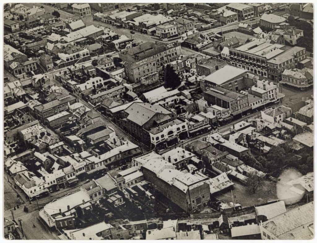 An old black and white photo of an ariel view of some buildings and streets