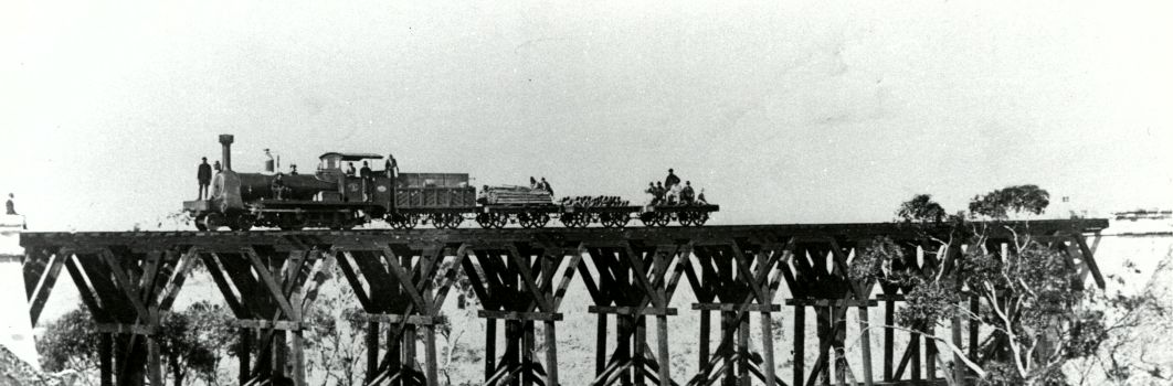 An old black and white photo of a train crossing a bridge.
