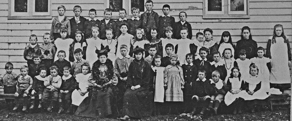 An old black and white photo of school kids posing for a photo.