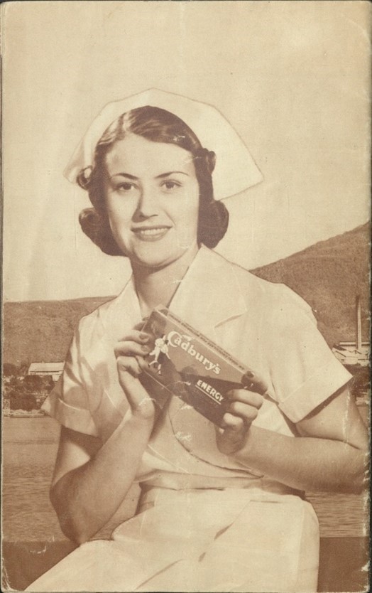 an old black and white photo of a woman in a factory workers uniform posing with a box of Cadbury's chocolate