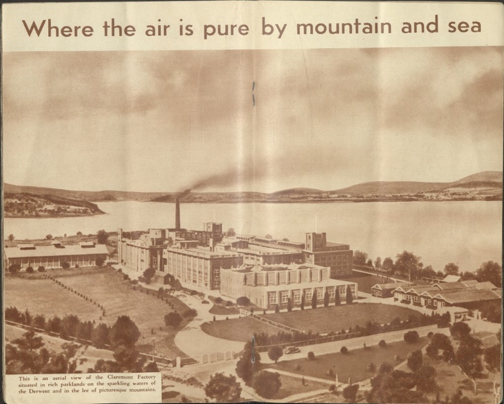 Anold black and white photo of an aerial view of the Claremont factory. Text at the top of the image reads: "Where the air is pure by mountain and sea" Text at the bottom left reads "This is an aerial view of the Claremont factory situated in rich parklands on the sparkling waters of the Derwent and in the lee of picturesque mountains."