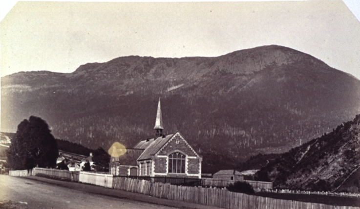 An old black and white photo of a picture of a school. seen from the other side of the road
