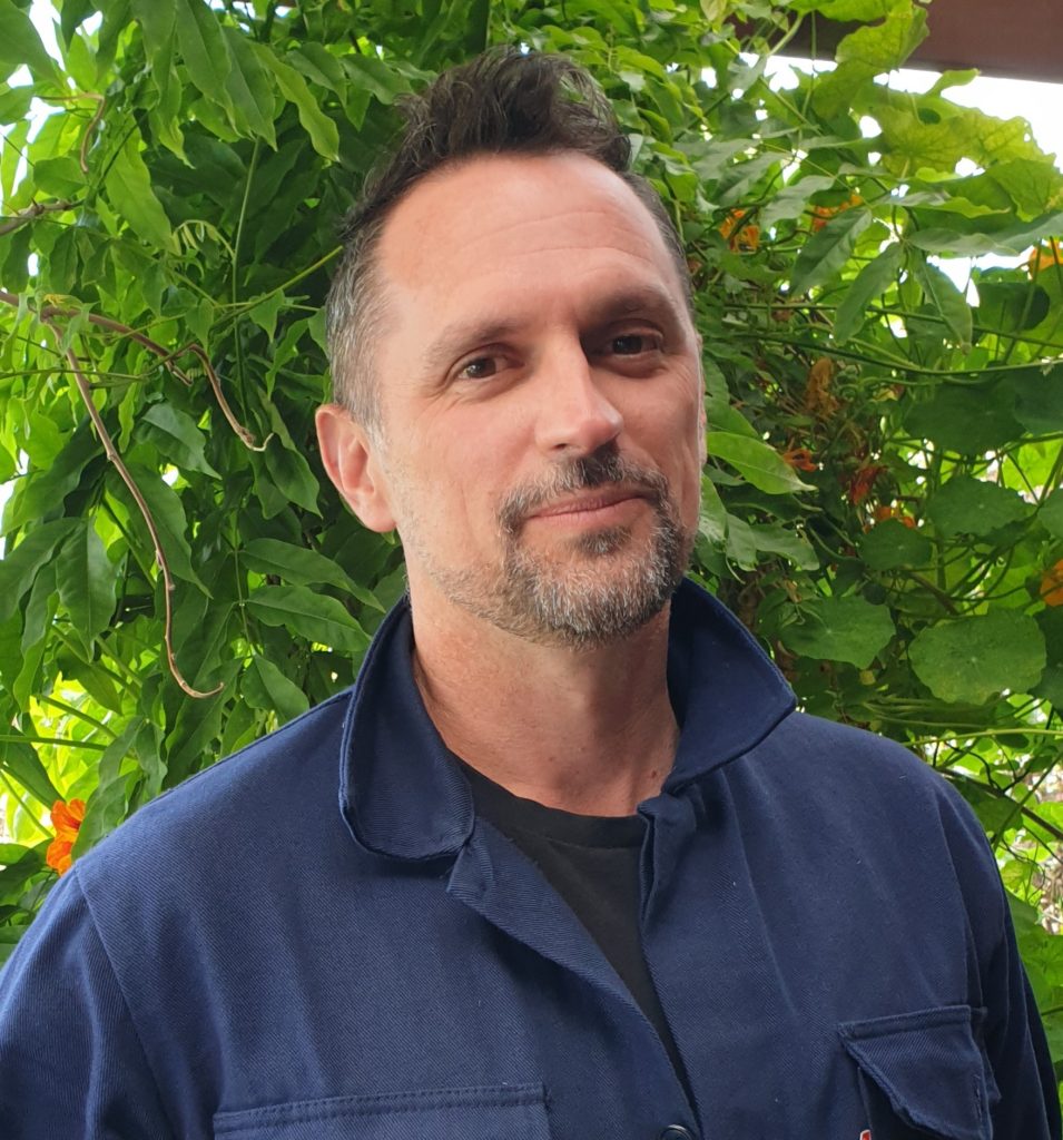 A person stands in front of plant wall.
