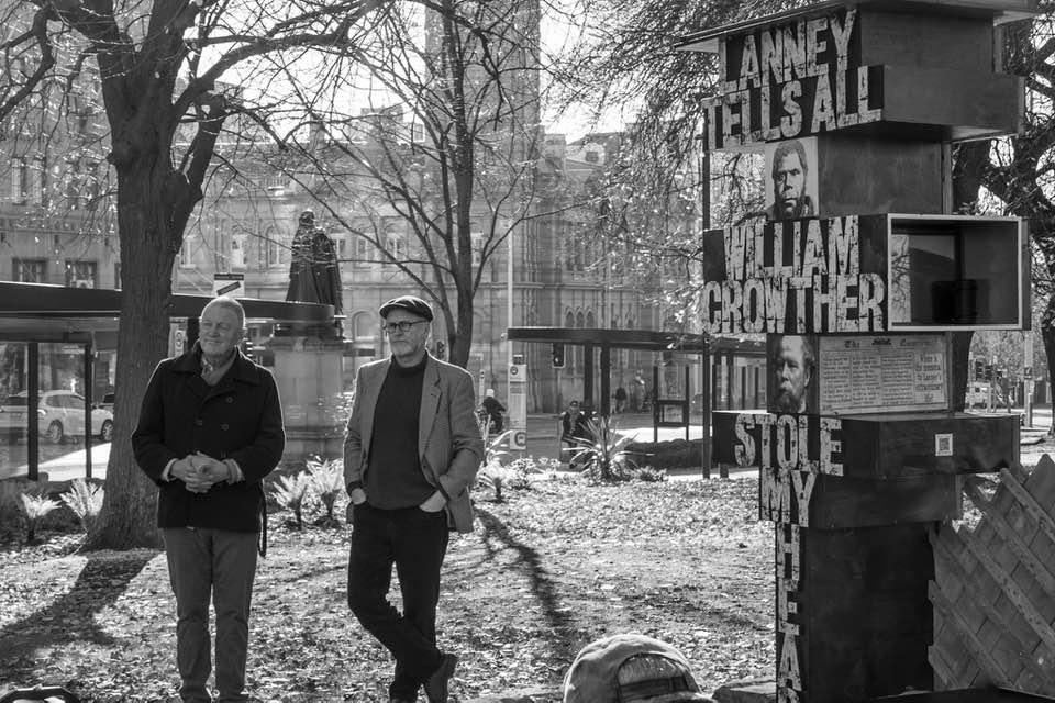 A modern black and white photo of Roger Scholes and Greg Lehman, standing next to the original Lanney Pillar sculpture in Franklin Square