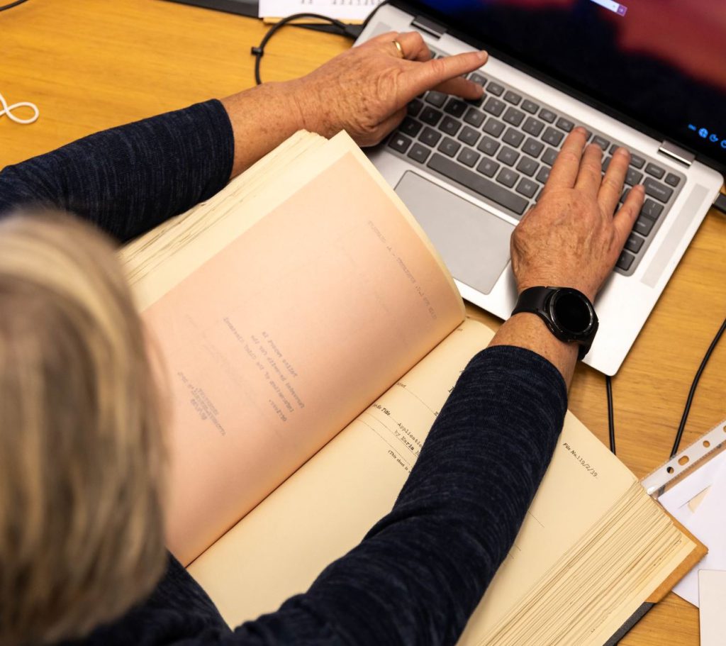 State Library and Archives support: A person typing on a keyboard while referring to archives.