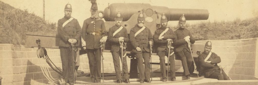 7 men in officers uniforms standing in front of a large cannon holding swords.