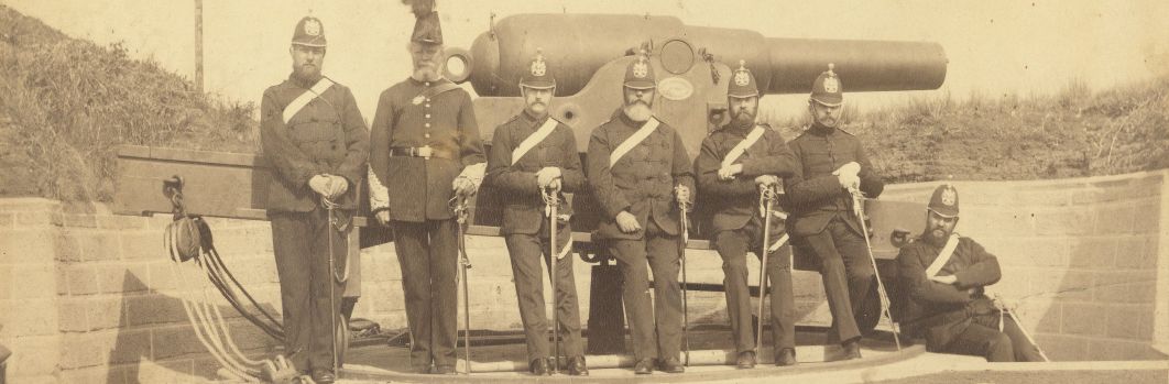 7 men in officers uniforms standing in front of a large cannon holding swords.